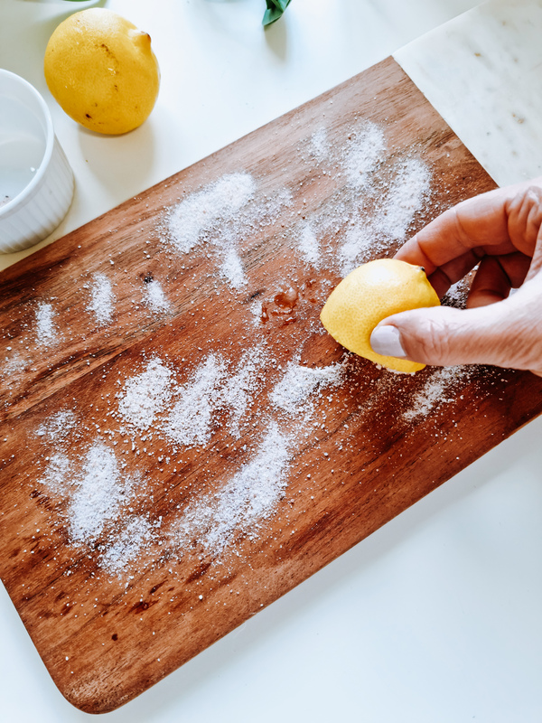 Cleaning a wooden chopping board with lemon and salt