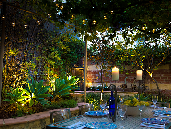 A table set for a dinner party in a beautifully lit backyard area
